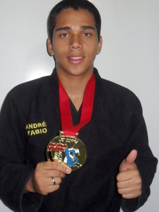 André Coutinho de kimono preto mostrando a medalha