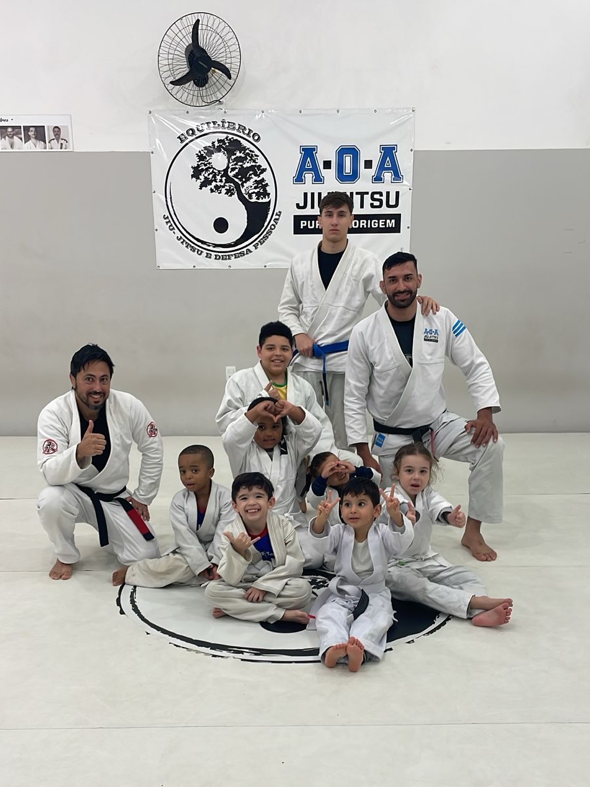 Crianças de kimono comemorando no tatame depois do treino