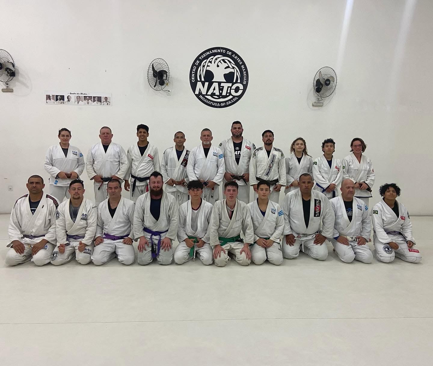 Turma de jiu-jitsu do Dojo Nato reunida embaixo do logo
